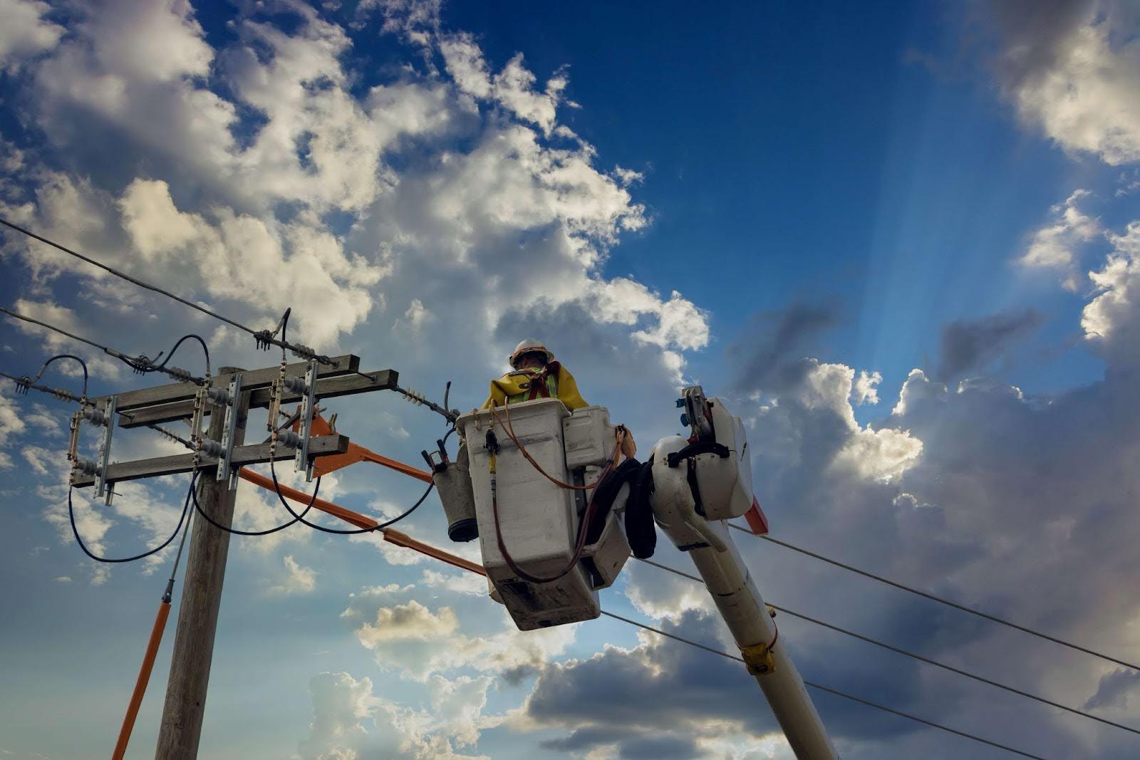 Male wearing a hard hat while working high on a collection of pole Bucket truck